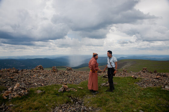 Albert Lin with a Mongolian herder among stone cairns on a ridge, Valley of the Khans expedition