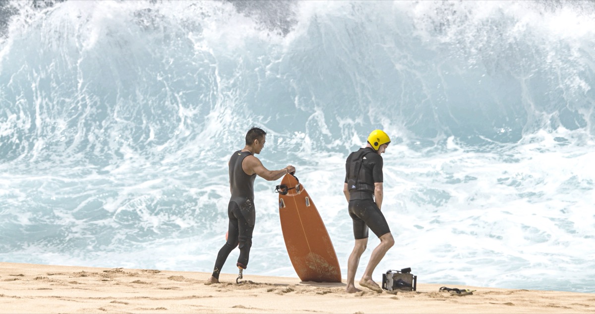 Albert Lin and a water safety crew on the sand with a heavy wave breaking behind